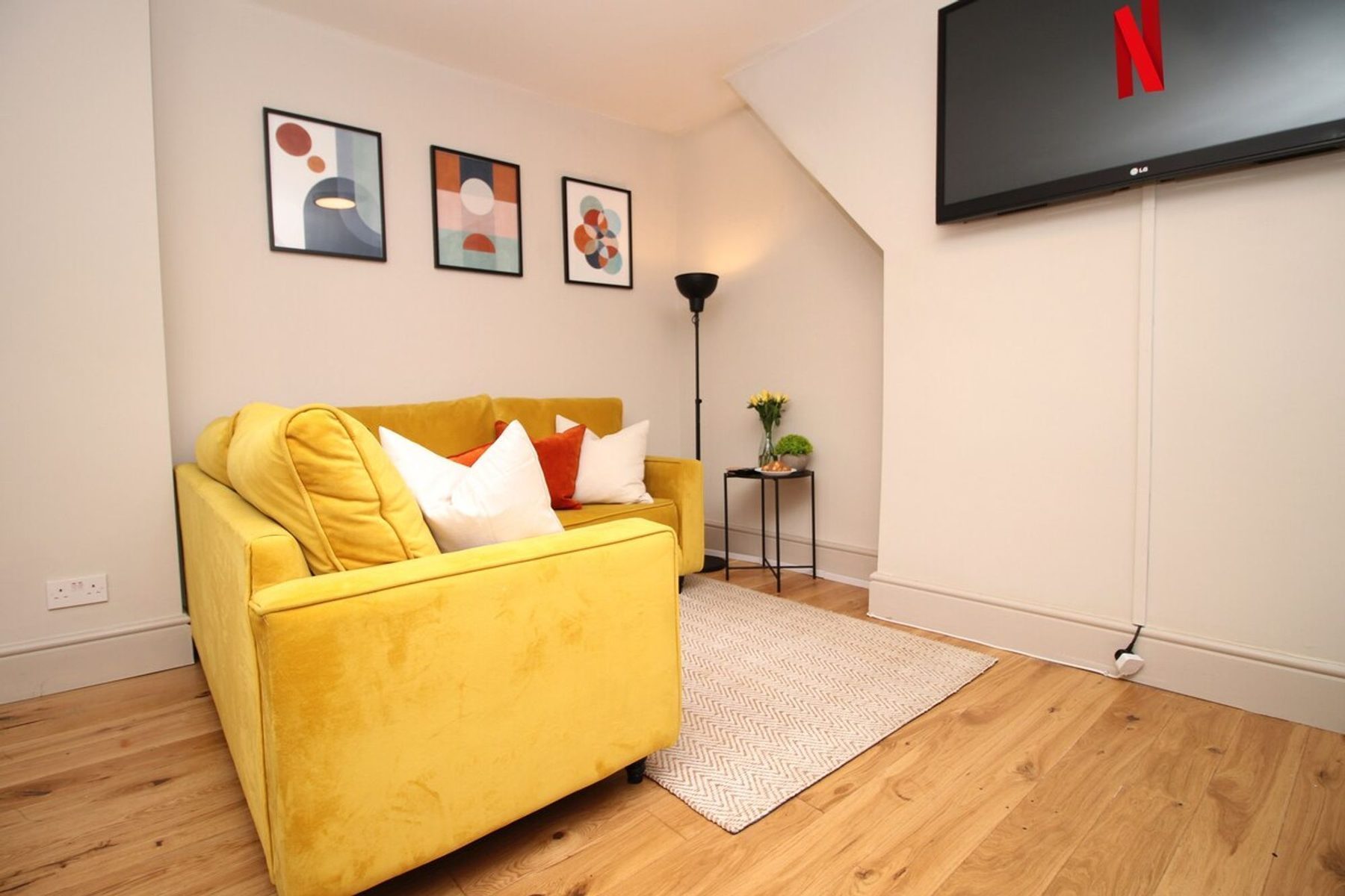A sofa corner with a lamp and a plant in an EKLiving apartment in Cardiff