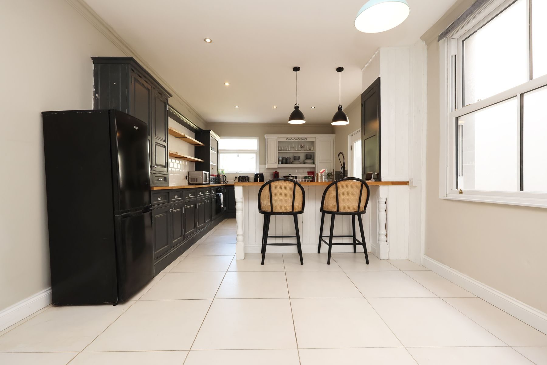 The long kitchen and dining room of an EKLiving house in Bridgend, with pendant lights over a breakfast bar