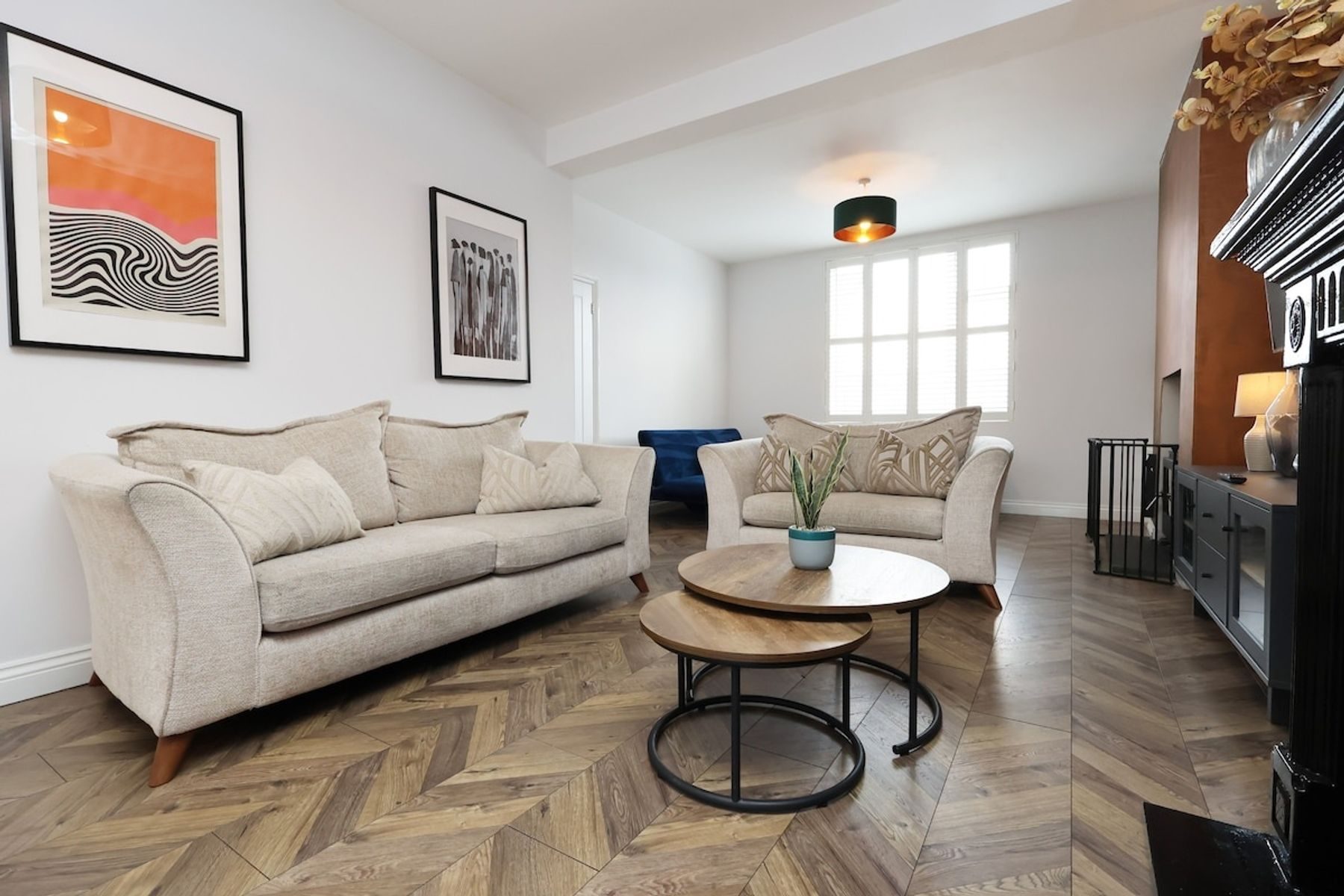 The living room of an EKLiving house in Pontypool: cream sofas, nested coffee tables and a herringbone floor